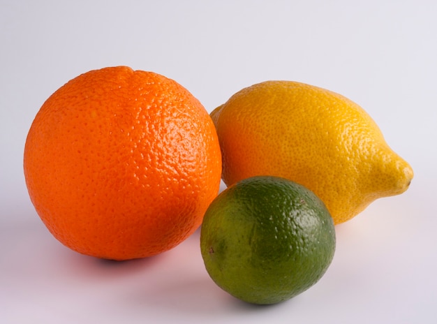 Frutas cítricas maduras limón, naranja y lima aislado sobre fondo blanco.