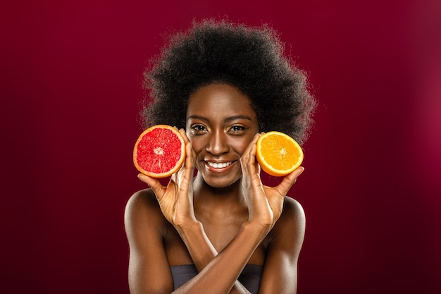 Frutas cítricas. mulher alegre e feliz sorrindo para você enquanto come frutas cítricas