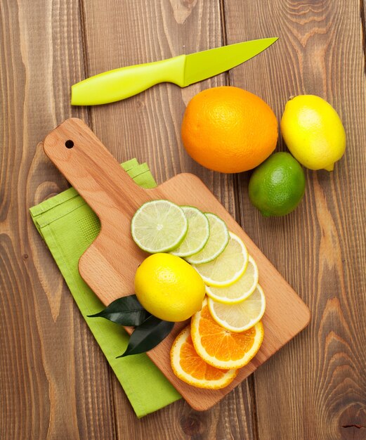 Frutas cítricas. Naranjas, limas y limones. Sobre fondo de mesa de madera