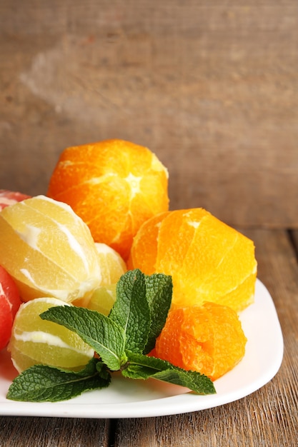 Frutas cítricas sem casca, no prato, sobre fundo de madeira