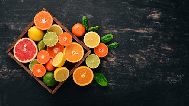 Frutas cítricas sortidas em uma caixa de madeira laranja tangerina toranja limão em um fundo de madeira vista superior copiar espaço