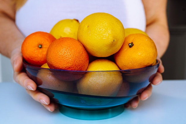 Frutas cítricas en un tazón en manos de mujer