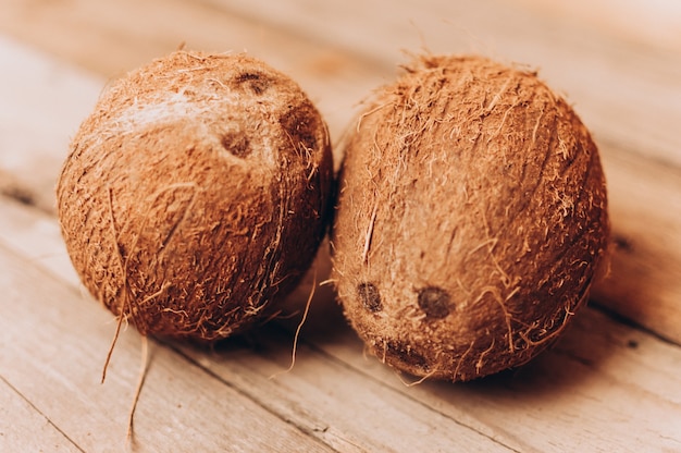 Frutas de coco tropical sobre un fondo de madera en estilo rústico.