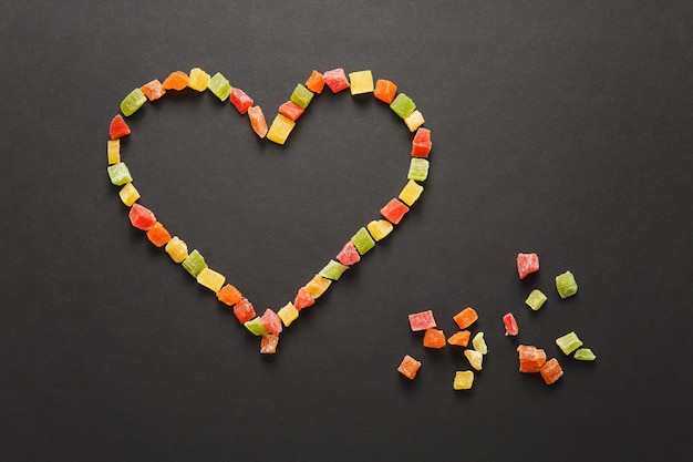 Frutas confitadas en forma de corazón aislado sobre fondo negro para el diseño. Tarjeta de San Valentín el 14 de febrero, concepto de vacaciones.