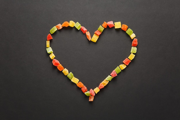 Frutas confitadas en forma de corazón aislado sobre fondo negro para el diseño. Tarjeta de San Valentín el 14 de febrero, concepto de vacaciones.