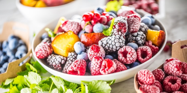 Frutas congeladas arándanos moras frambuesa grosella melocotón y hierbas melisa.