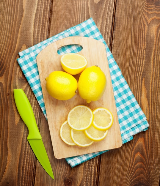 Frutas cortadas de limão na tábua sobre a mesa de madeira. Vista de cima