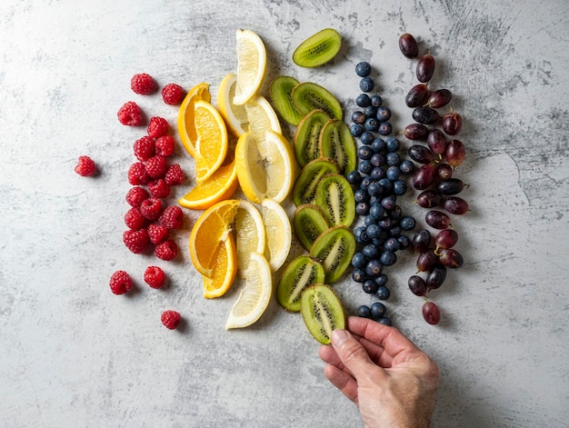 Frutas cortadas e dispostas na ordem das cores do arco-íris uma mão coloca as frutas em ordem