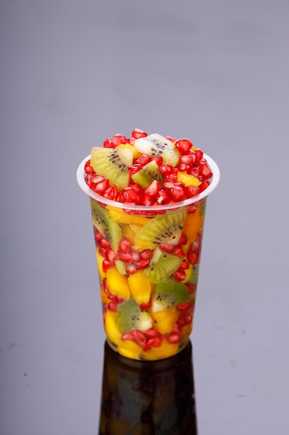 Frutas cortadas mistas dispostas em um vidro transparente com fundo branco, isoladas.