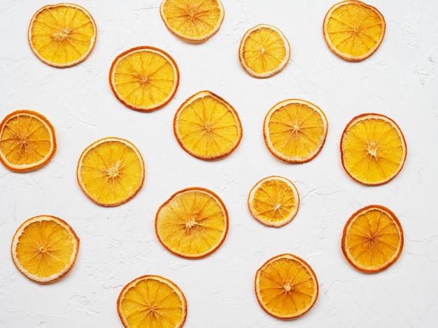 Frutas crocantes desidratadas para decorar pratos para bebidas e sobremesas. Fatias de laranja secas ou batatas fritas em fundo branco. Pilha, pilha de laranjas crocantes secas ao sol. Lanche de refeição saudável. Vista do topo.