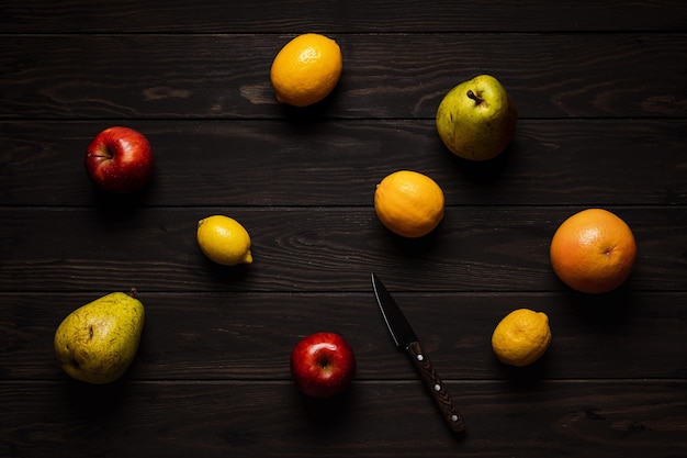 Frutas y cuchillo sobre un fondo de madera Fotografía cenital Limón pomelo manzana pera cítricos