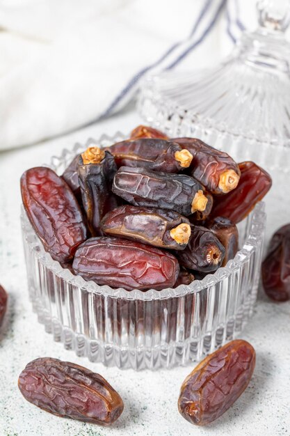 Foto frutas de dátiles en fondo de piedra dátiles orgánicos de medjoul en un cuenco de vidrio comida de ramadán de cerca