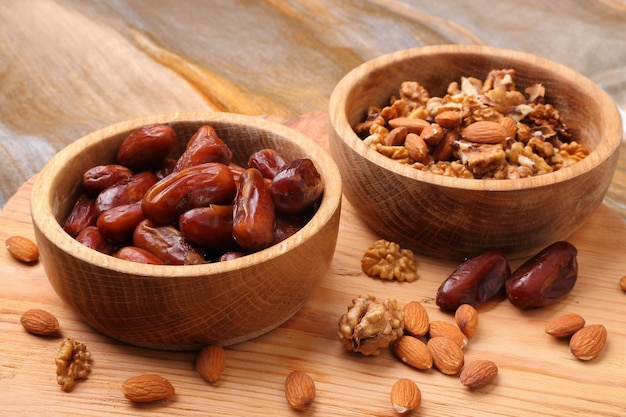 Frutas, dátiles y nueces en primer plano del tazón de madera en la mesa