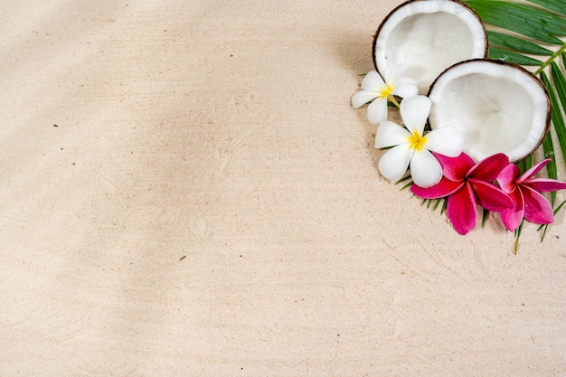 Frutas de coco e flores de frangipani no fundo da praia de areia.