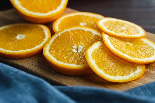 Frutas de laranjas fatiadas perto de têxteis de denim na placa de madeira Conceito mínimo de frutas cítricas de laranja suculenta