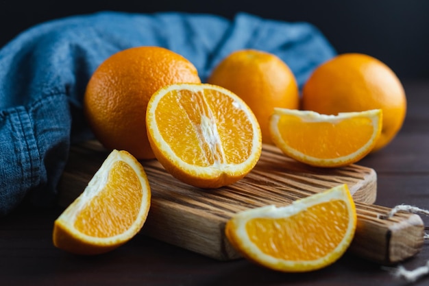 Frutas de laranjas fatiadas perto de têxteis de denim na placa de madeira Conceito mínimo de frutas cítricas de laranja suculenta