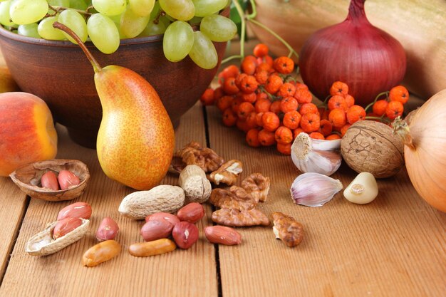 Frutas de outono vegetais nozes e bagas em uma placa de barro em um fundo de madeira comida vegana em uma mesa de madeira fechada