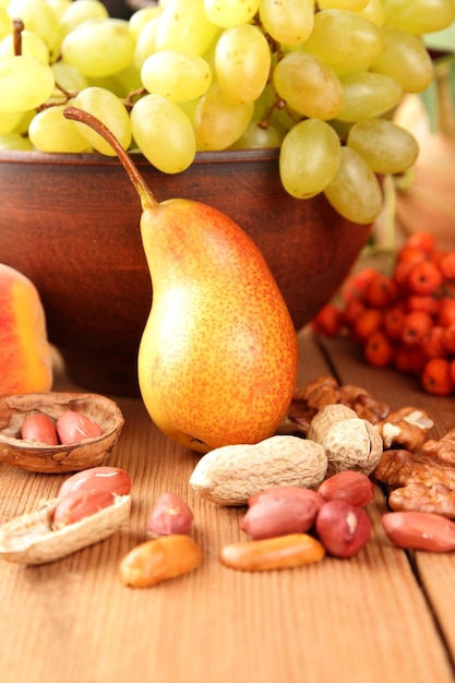 Frutas de outono vegetais nozes e bagas em uma placa de barro em um fundo de madeira Comida vegana em uma mesa de madeira fechada