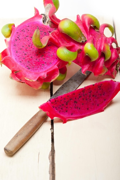 Foto frutas de pitaya com uma faca de cozinha na mesa