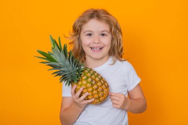 Frutas de verão Garoto com abacaxi no estúdio Retrato de estúdio de uma criança bonita segura abacaxi isolado em fundo amarelo