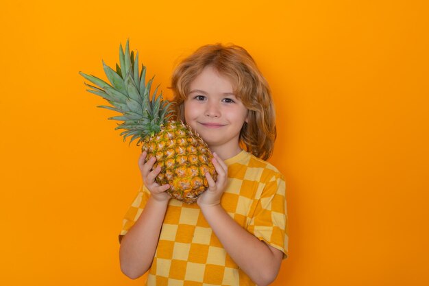 Frutas de verão Garoto com abacaxi no estúdio Retrato de estúdio de uma criança bonita segura abacaxi isolado em fundo amarelo