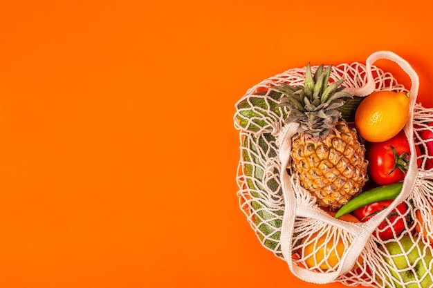 Frutas e legumes frescos em malha de saco, vista superior.