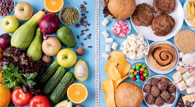 Foto frutas e legumes versus doces e fast food vista superior plana sobre fundo azul