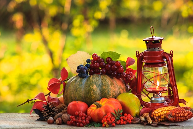 Frutas e nozes, abóboras na mesa ao ar livre e lamparina a querosene - outono aconchegante