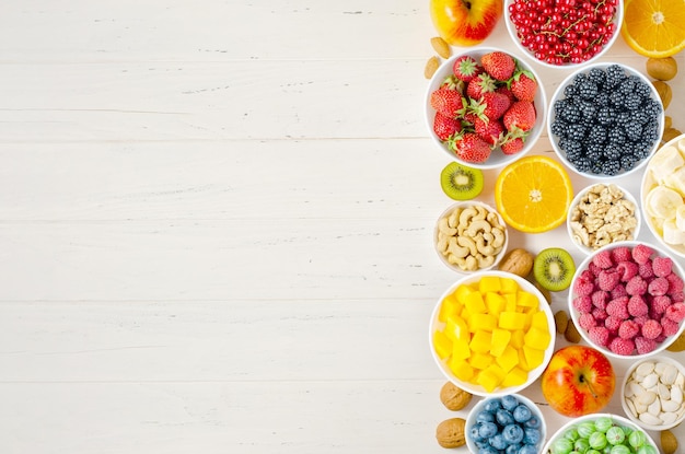 Frutas e nozes em um fundo branco de madeira Comida vegetariana Copie o espaço