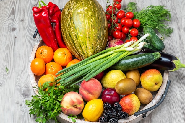 Frutas e vegetais em uma bandeja de madeira no fundo cinza da mesa de madeira