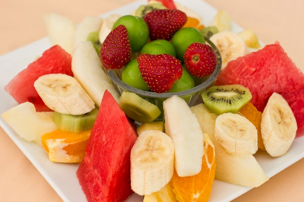 Frutas em um prato. ameixa verde, morango, banana, kiwi, melancia, laranja e maçã.