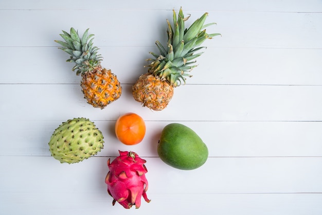 Frutas exóticas de verão fresco em branco. Fruta do dragão, abacaxi, caqui, manga, annona cherimola plana leigos com espaço de cópia gratuita.