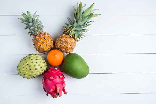 Frutas exóticas de verão fresco em branco. Fruta do dragão, abacaxi, caqui, manga, annona cherimola plana leigos com espaço de cópia gratuita.