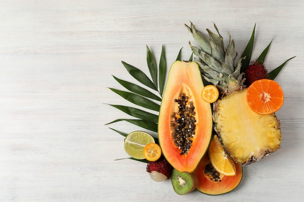 Frutas exóticas em fundo branco de madeira, espaço para texto.