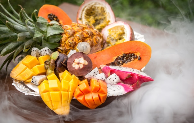 Frutas exóticas en el humo de un primer plano de la cachimba en una bandeja