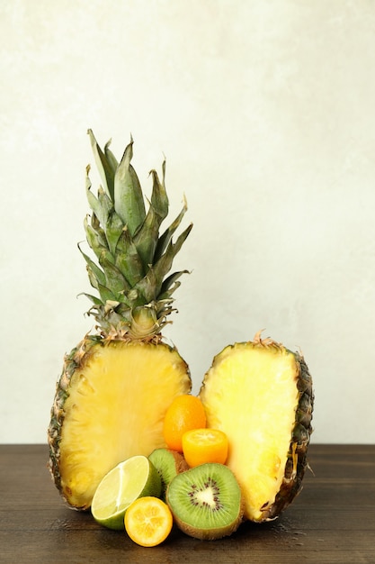 Frutas exóticas en mesa de madera sobre fondo blanco.