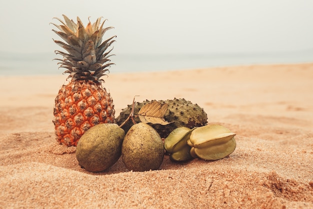 Frutas exóticas na areia perto do oceano