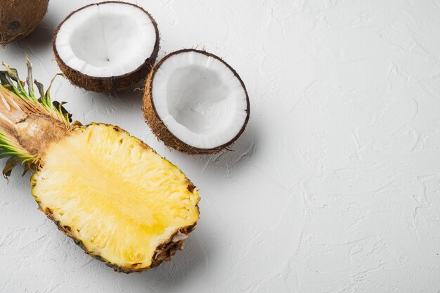 Frutas exóticas, piña y coco, sobre fondo de mesa de piedra blanca, vista superior plana, con espacio para copiar texto