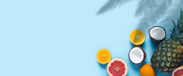 Frutas exóticas sobre un fondo azul. Piña, coco, naranja, pomelo