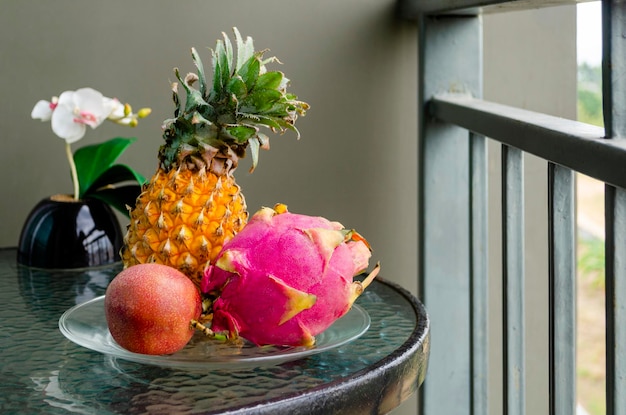 Foto frutas exóticas tailandesas piña fruta del dragón fruta de la pasión en una mesa de cristal