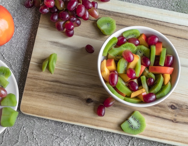 Foto frutas fatiadas em salada de madeira