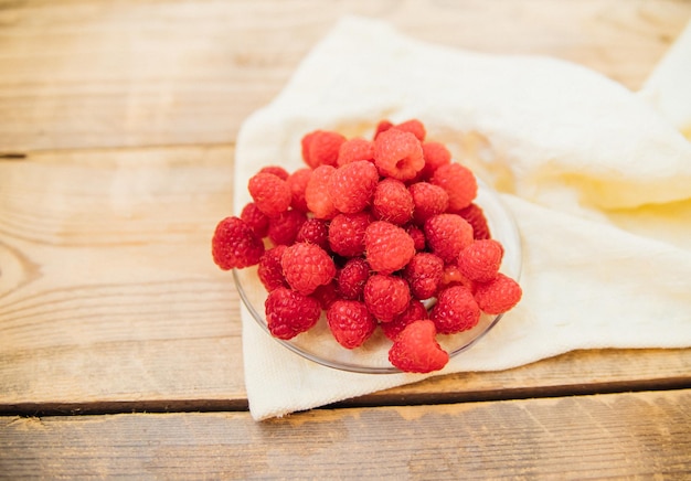 Frutas de frambuesa en un platillo pequeño un montón de bayas de verano sobre un fondo de madera Fondo de verano Aperitivo o postre jugoso