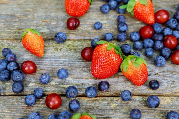 Frutas de las fresas de la uva de los arándanos en la placa de madera en fondo de madera