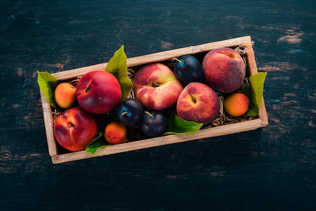 Frutas frescas en una caja de madera Albaricoque melocotón nectarina ciruela Sobre un fondo de madera Vista superior Espacio libre para su texto