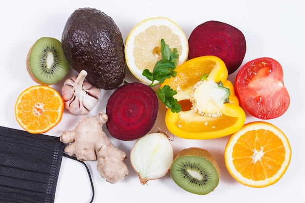 Foto frutas frescas com vegetais e máscara protetora fonte de vitaminas e minerais alimentação benéfica em tempos de covid19 fundo branco