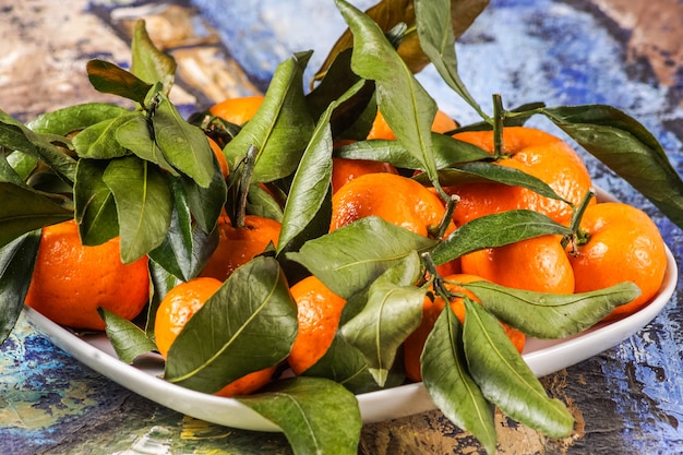 frutas frescas das tangerinas com folhas em uma placa.