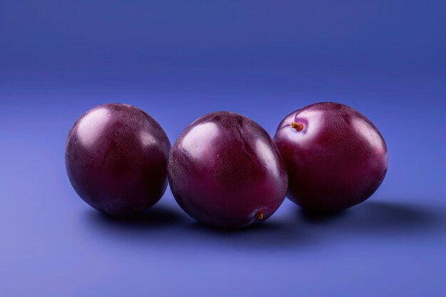 Frutas frescas de ameixa em fundo colorido