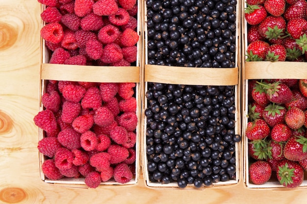 Frutas frescas de groselha e morangos em cestas com fundo de madeira