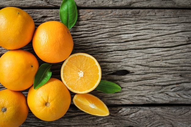 Frutas frescas de laranja com folhas na mesa de madeira