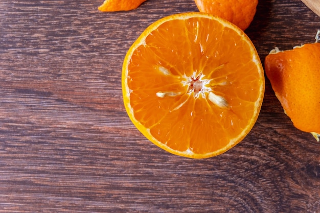 Frutas frescas de laranja e laranja cortadas ao meio em uma mesa de madeira